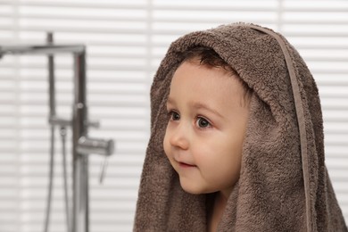 Photo of Cute little boy wrapped with towel after washing hair in bathroom. Space for text