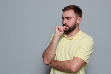 Photo of Man biting his nails on grey background, space for text. Bad habit