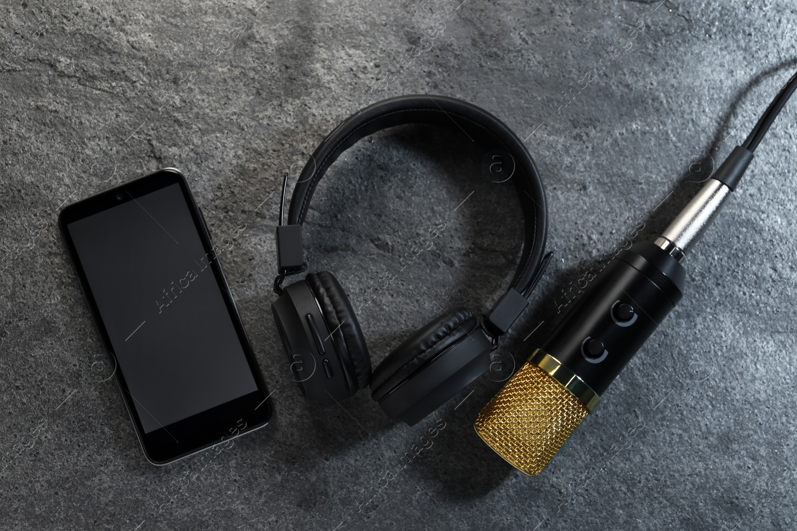 Photo of Smartphone with blank screen, headphones and microphone on grey textured background, flat lay. Sound recording and reinforcement