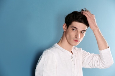 Portrait of young man with beautiful hair on color background