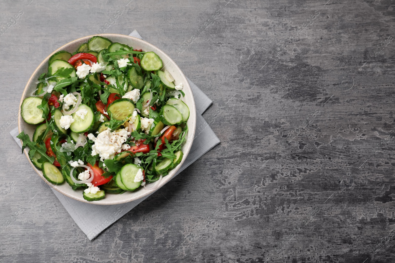 Photo of Plate of delicious cucumber salad on grey table, top view. Space for text