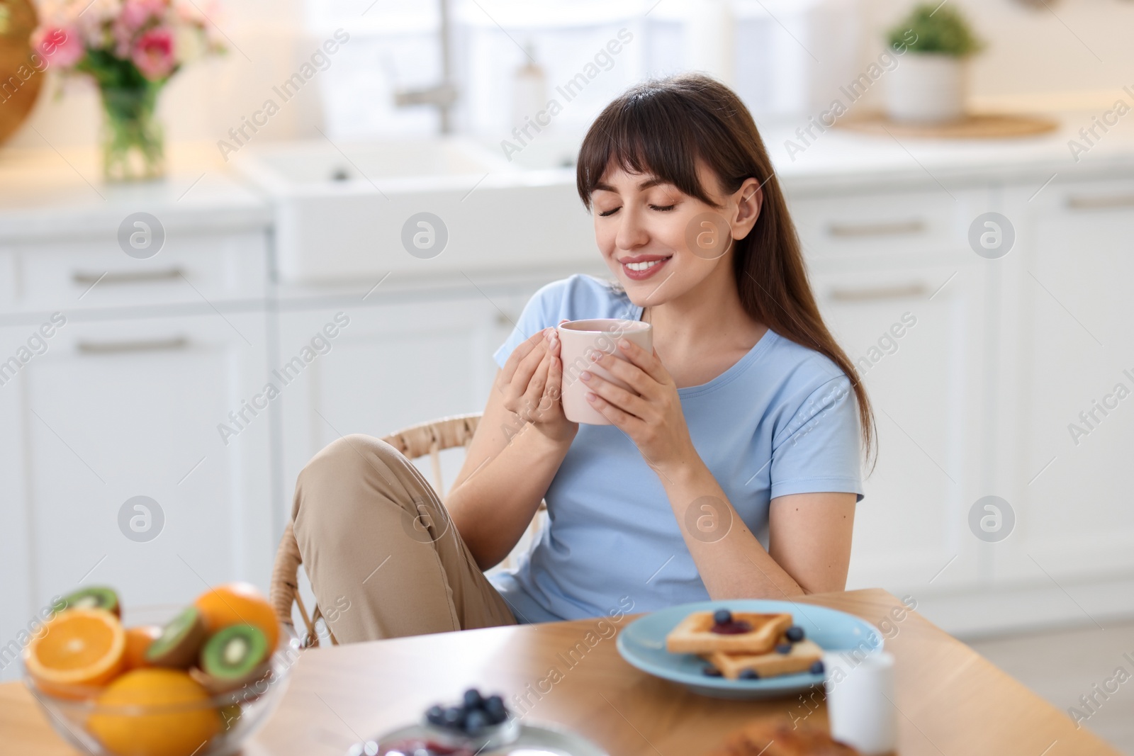 Photo of Smiling woman drinking coffee at breakfast indoors