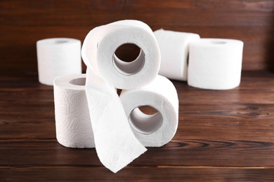 Photo of Many soft toilet paper rolls on wooden table, closeup