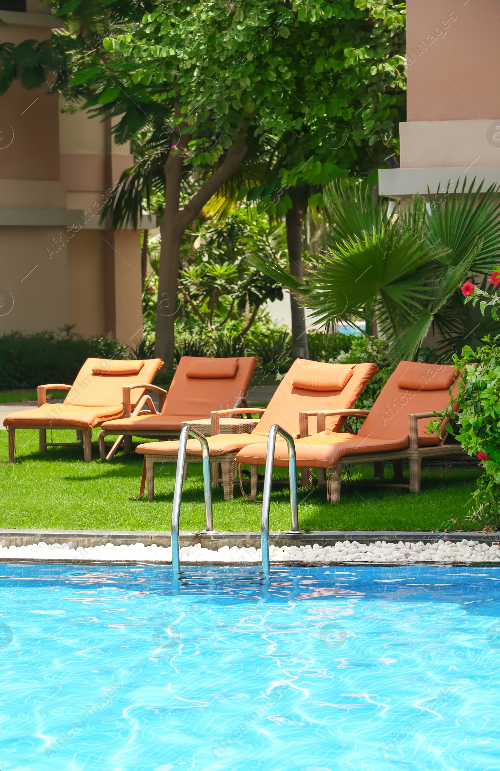 Photo of Sunbeds near modern swimming pool at resort