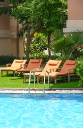 Photo of Sunbeds near modern swimming pool at resort