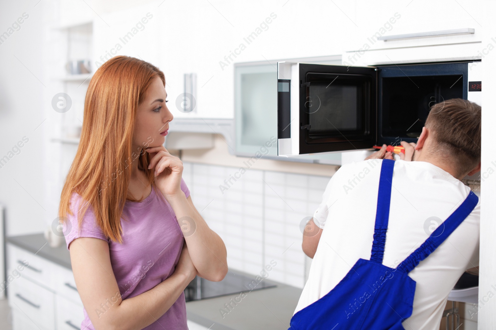 Photo of Housewife and repairman near microwave oven in kitchen