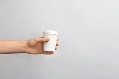 Photo of Woman holding takeaway paper coffee cup on light background. Space for design
