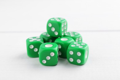 Many green game dices on white wooden table