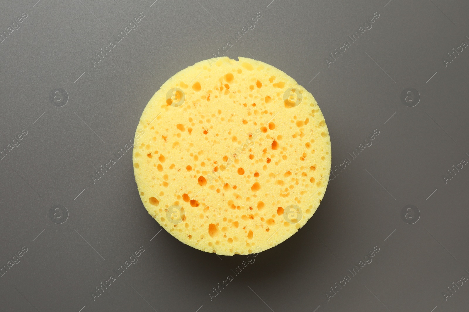 Photo of New yellow sponge on grey background, top view