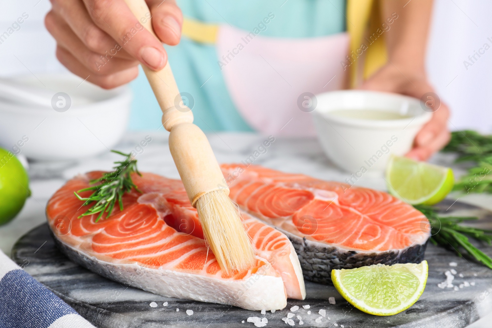 Photo of Woman marinating fresh raw salmon at table, closeup. Fish delicacy