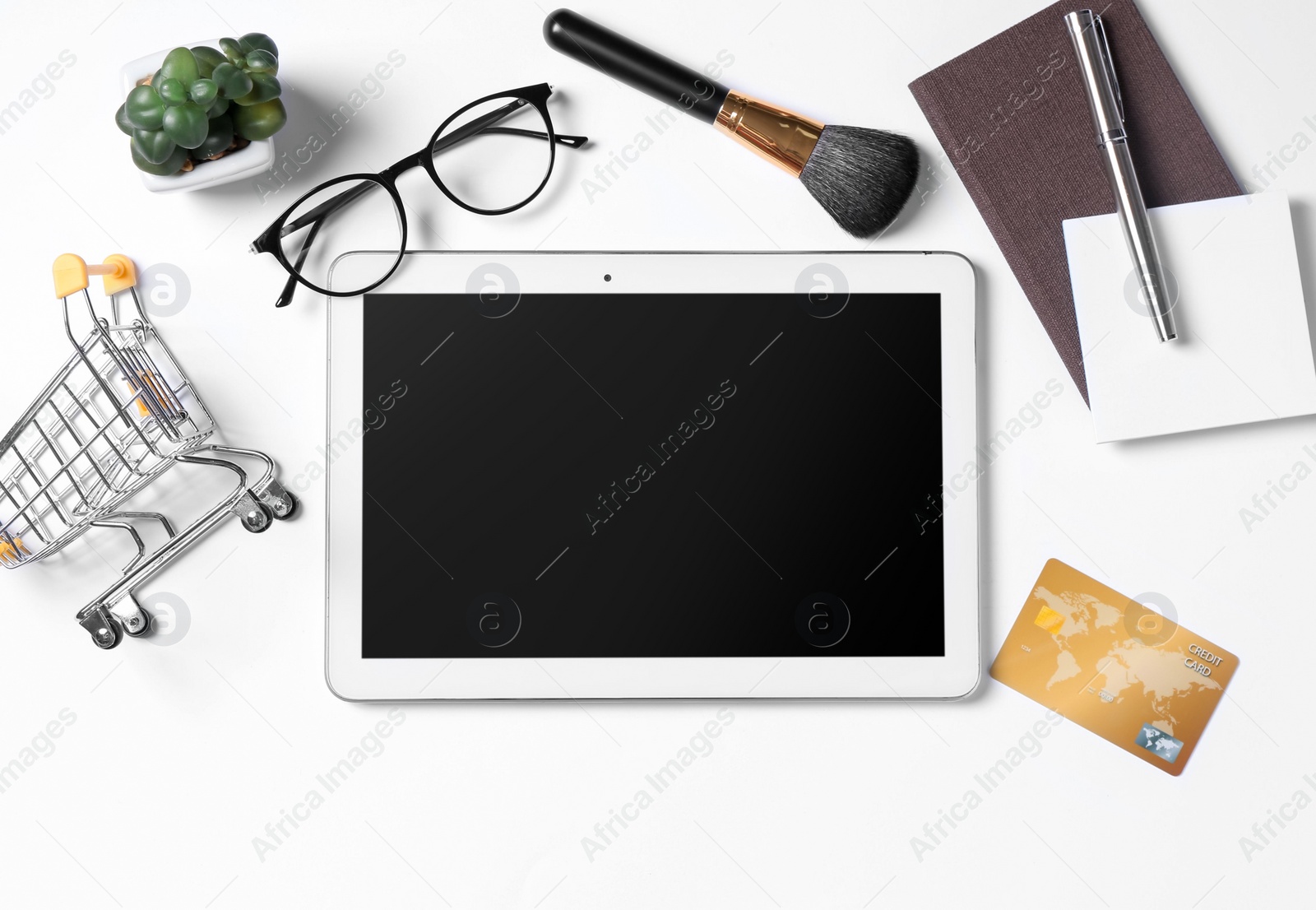 Photo of Online store. Tablet, shopping cart, credit card, glasses, houseplant and stationery on white background, flat lay