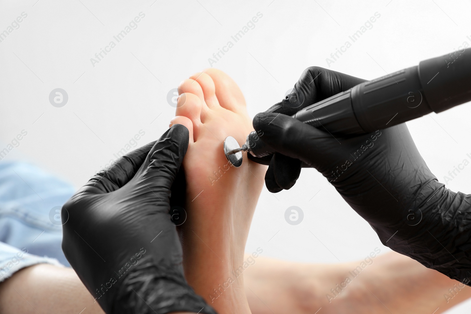 Photo of Professional master making hardware pedicure for client in beauty salon, closeup