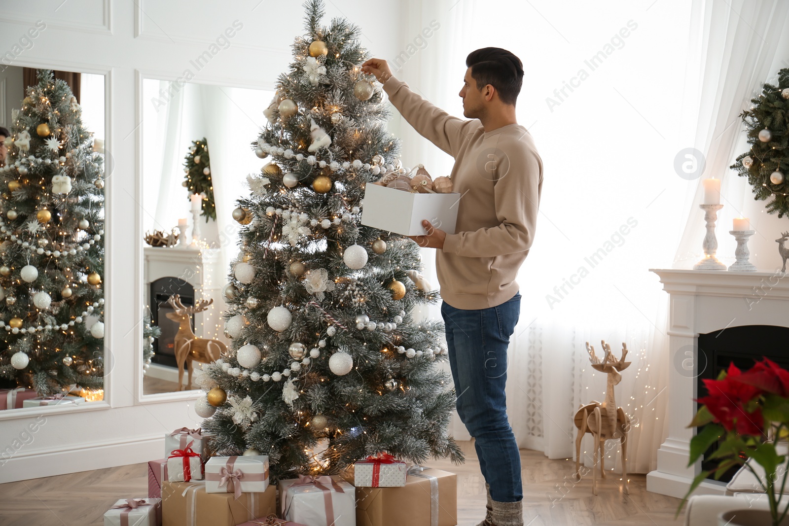 Photo of Man decorating Christmas tree in beautiful room interior