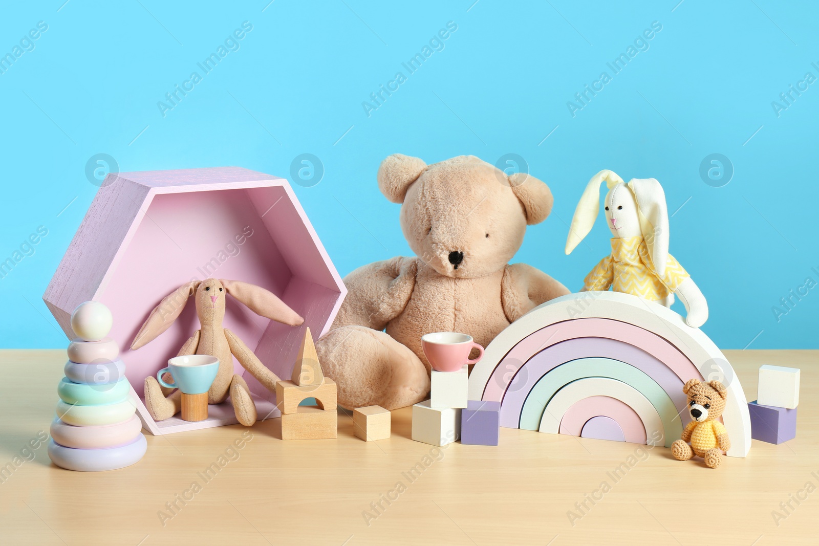 Photo of Many different toys on wooden table against light blue background