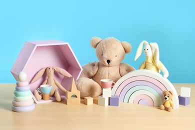 Many different toys on wooden table against light blue background