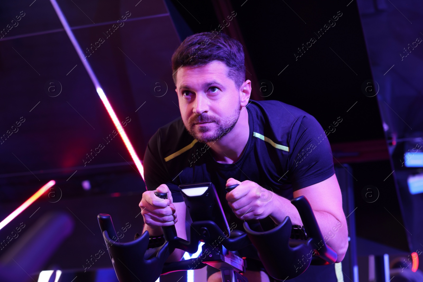 Photo of Man training on exercise bike in fitness club