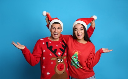 Couple in Christmas sweaters and Santa hats on blue background