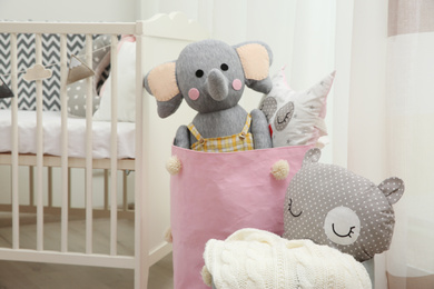 Photo of Basket with different toys near crib in baby room. Interior design