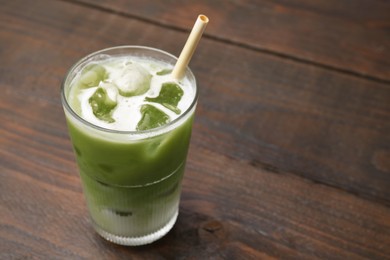 Photo of Glass of tasty iced matcha latte on wooden table. Space for text