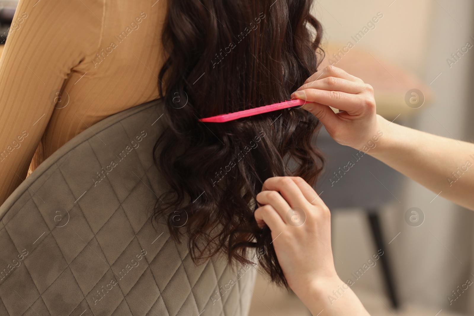 Photo of Hair styling. Professional hairdresser combing woman's hair indoors, closeup