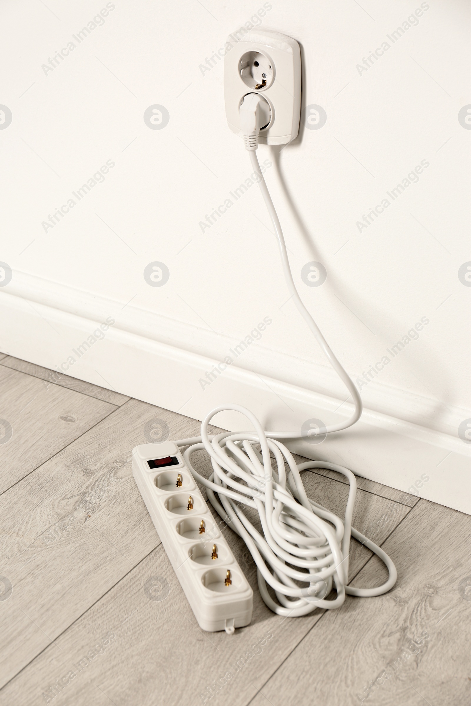 Photo of Extension cord with power plug in socket indoors. Electrician's professional equipment