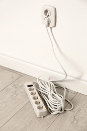 Extension cord with power plug in socket indoors. Electrician's professional equipment