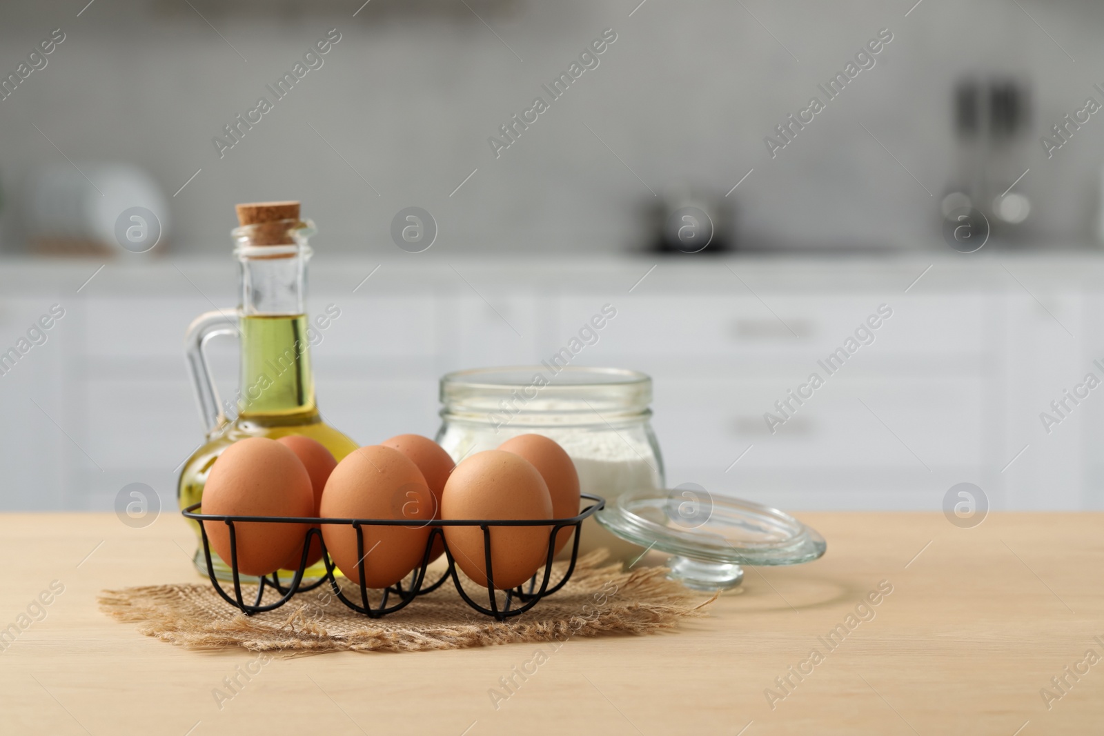 Photo of Eggs, flour and oil on wooden table in kitchen. Space for text