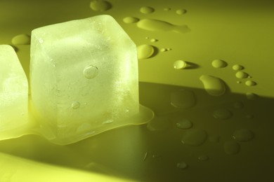 Crystal clear ice cubes on yellow background, closeup. Space for text