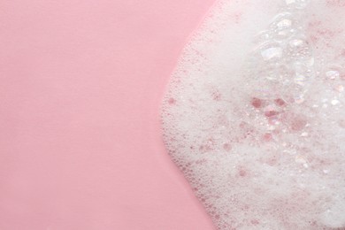 Photo of Fluffy bath foam on pink background, top view. Space for text