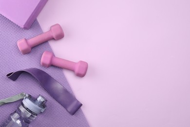 Photo of Two dumbbells, yoga block, mat, fitness elastic band and bottle on violet background, flat lay. Space for text