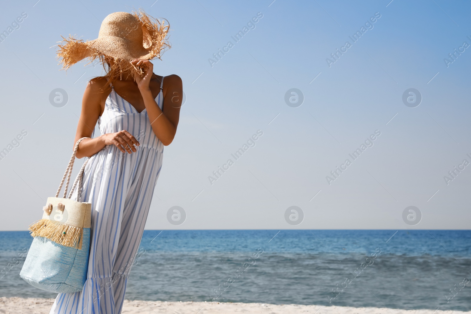 Photo of Woman with beach bag walking on sand near sea. Space for text