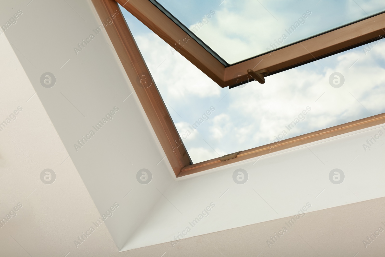 Photo of Open skylight roof window on slanted ceiling in attic room, low angle view