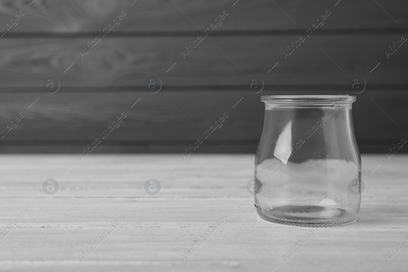 Photo of Empty glass jar on white wooden table, space for text