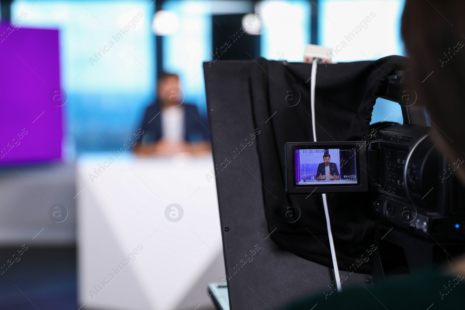 Photo of Presenter and video camera operator working in studio. News broadcasting