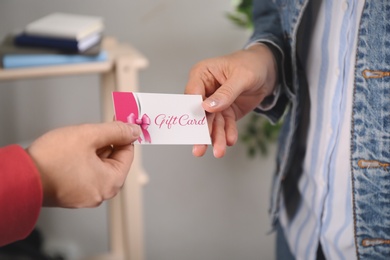 Photo of Women with gift card on blurred background, closeup 