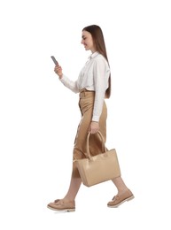 Young woman in casual outfit using smartphone while walking on white background