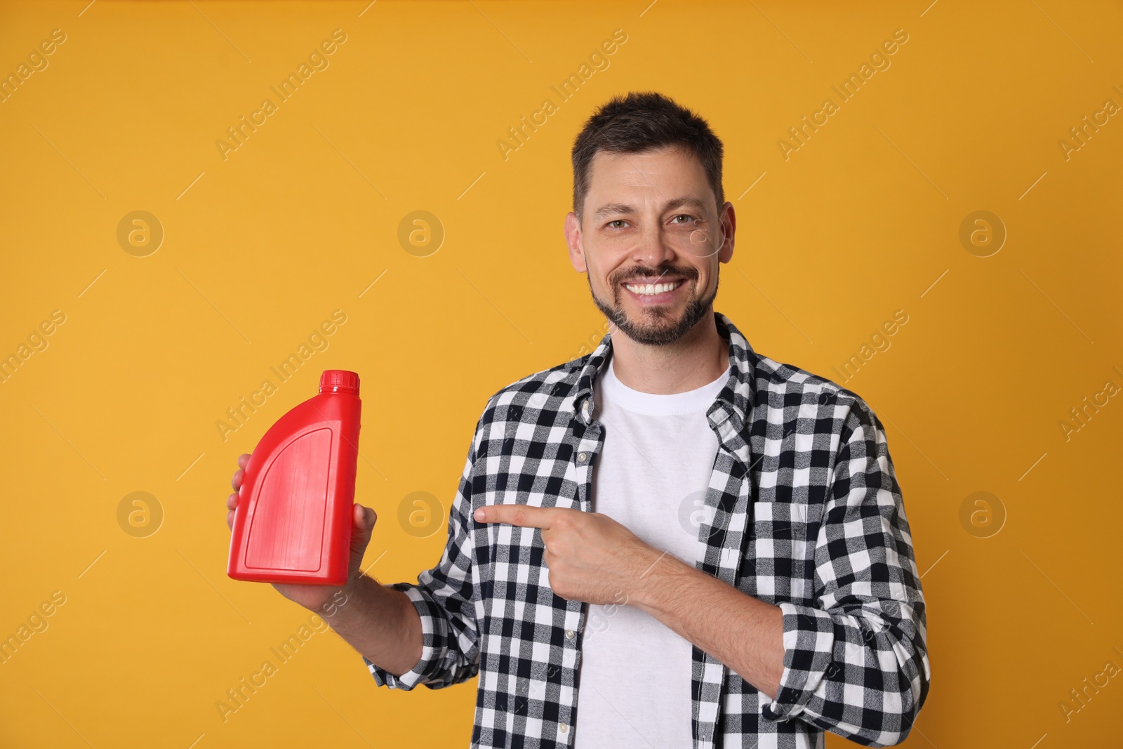 Photo of Man pointing at red container of motor oil on orange background
