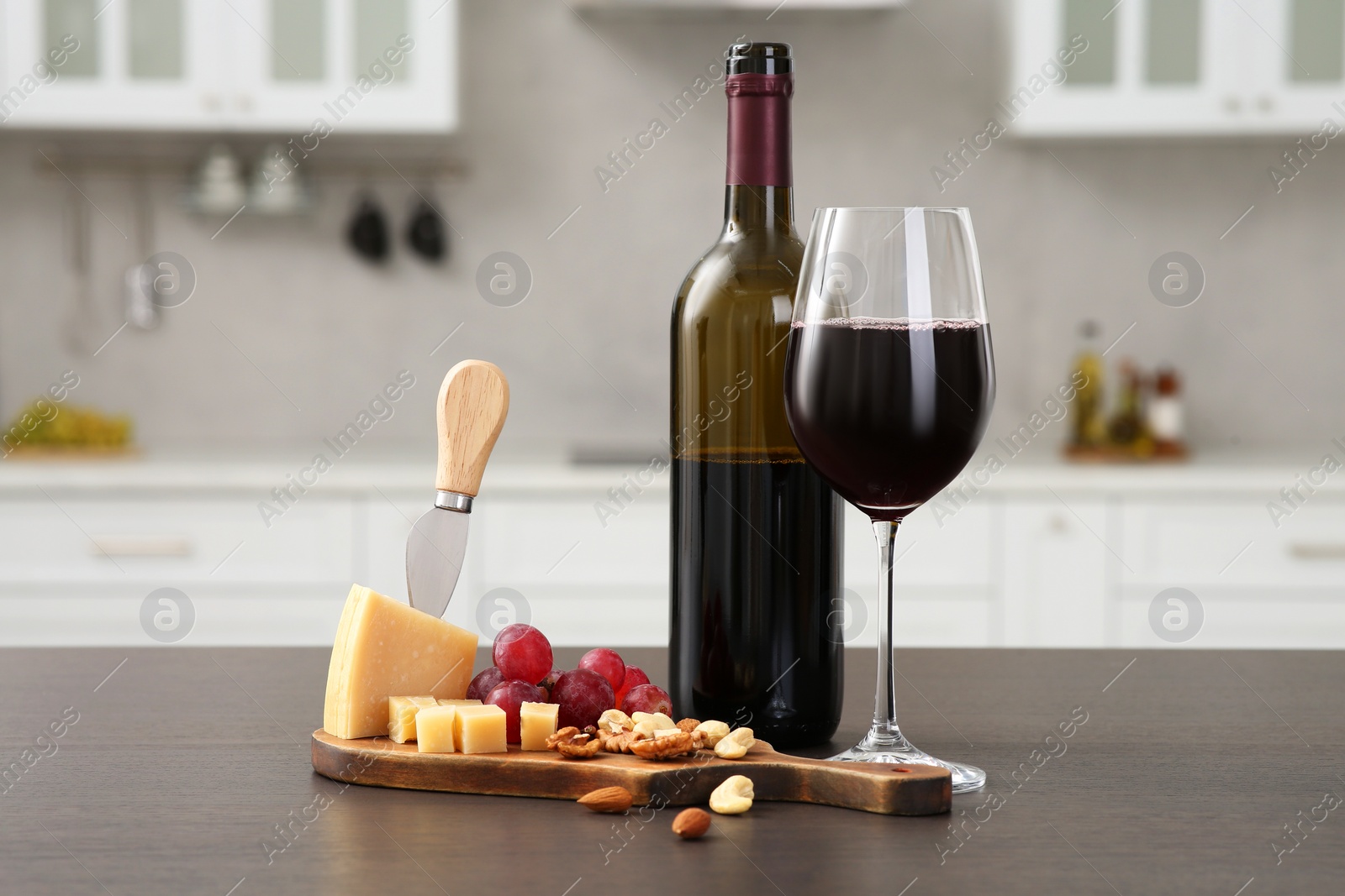 Photo of Red wine with fruits and, nuts, grape and cheese on countertop in kitchen