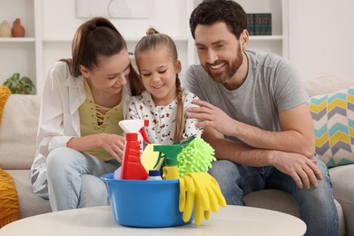 Spring cleaning. Family with basin of different detergents in living room