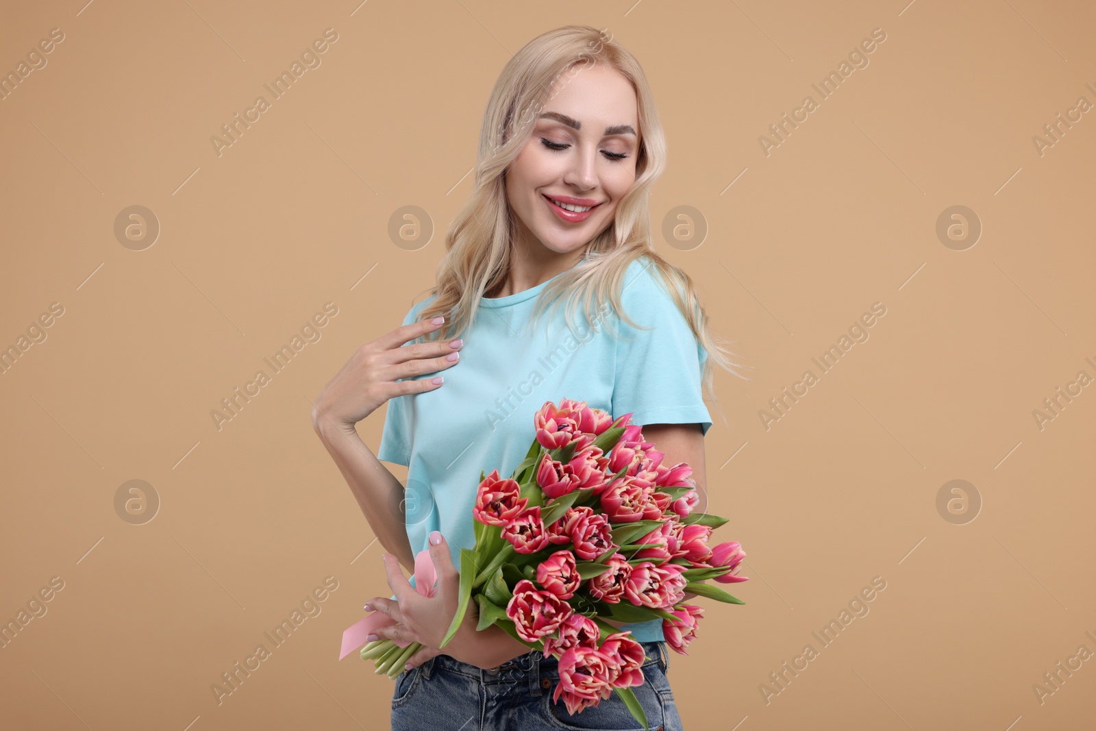 Photo of Happy young woman with beautiful bouquet on beige background