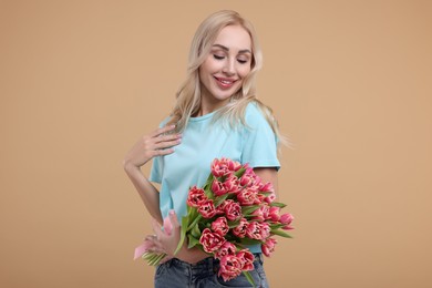 Happy young woman with beautiful bouquet on beige background