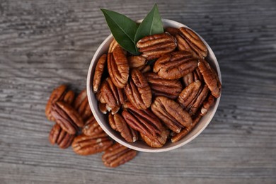 Photo of Tasty pecan nuts on grey wooden table, flat lay