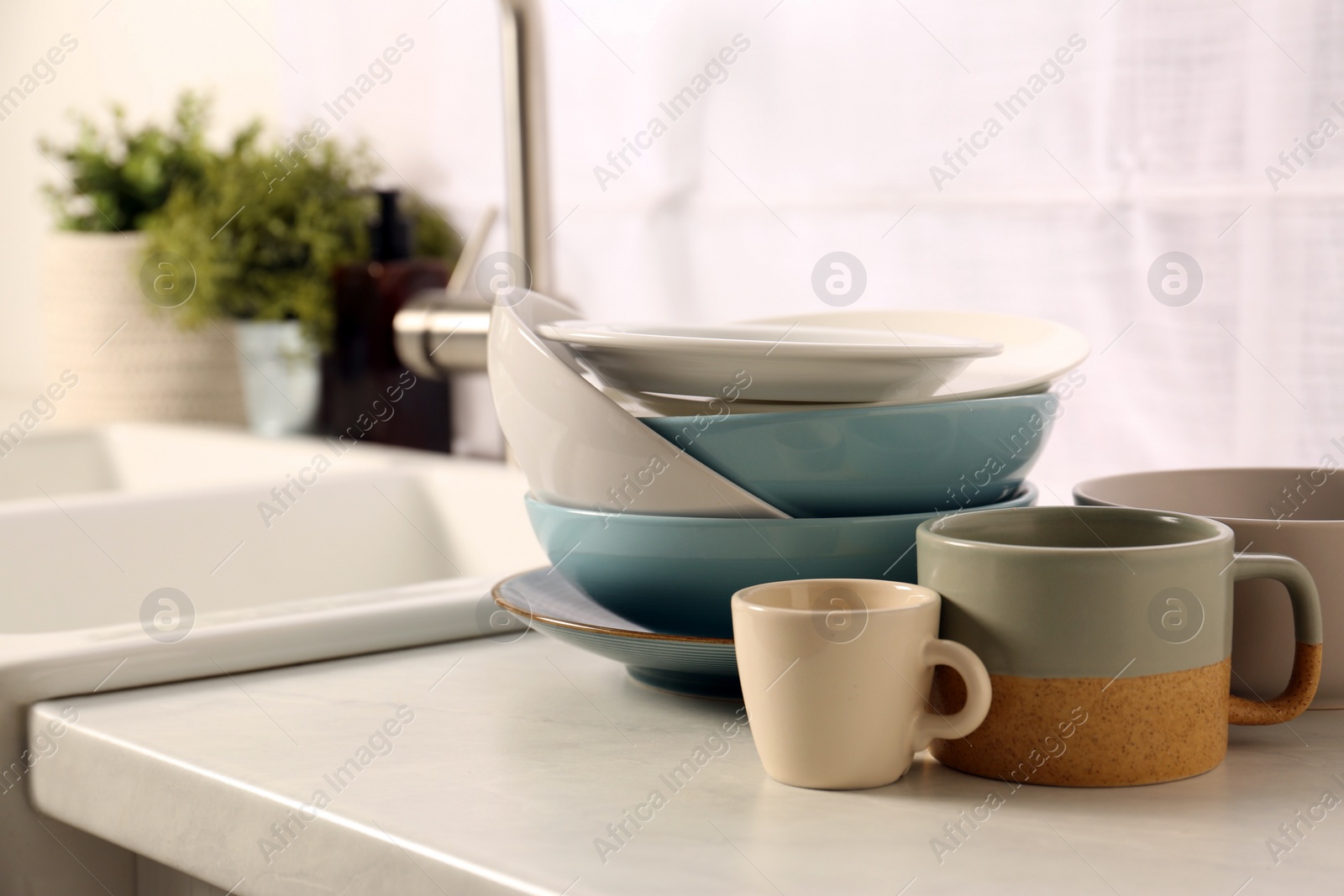 Photo of Clean tableware on light countertop near sink in kitchen