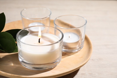 Photo of Plate with burning small candles on white wooden table, closeup