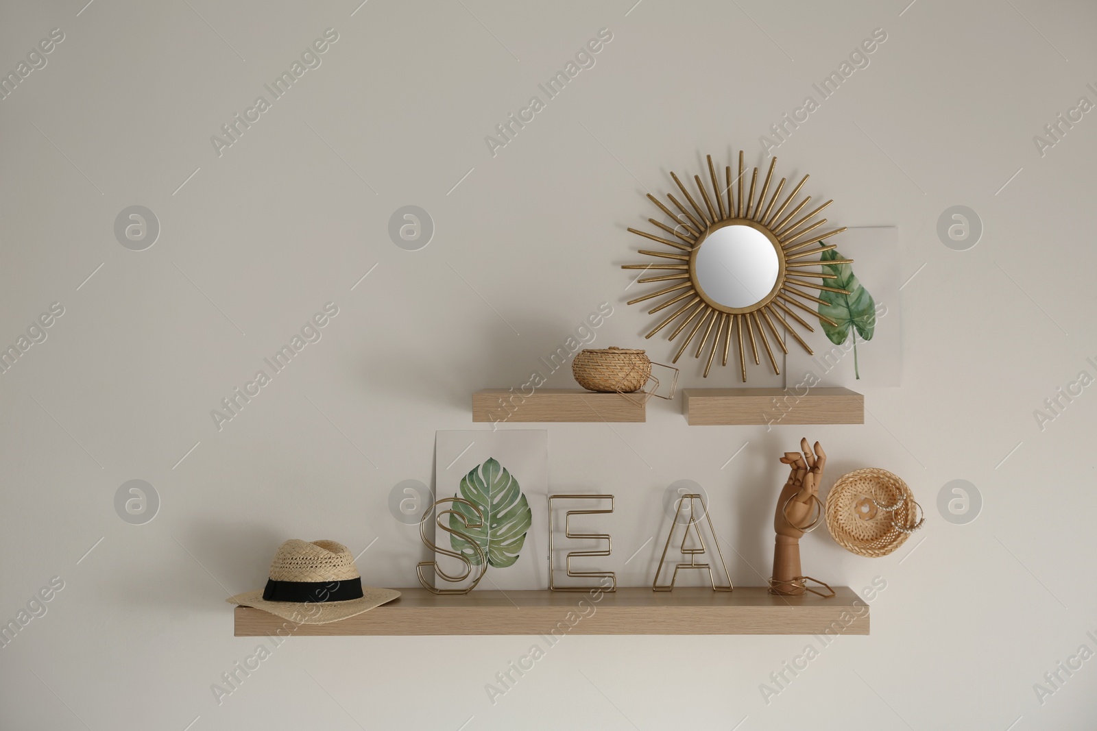 Photo of Wooden shelves with women's accessories and different decorative elements on light wall. Space for text