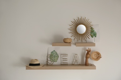 Photo of Wooden shelves with women's accessories and different decorative elements on light wall. Space for text