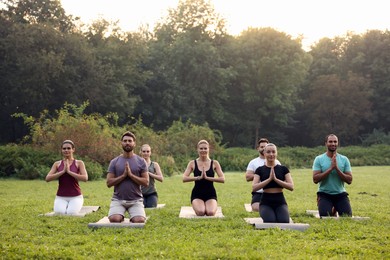 Photo of Group of people practicing yoga on mats outdoors