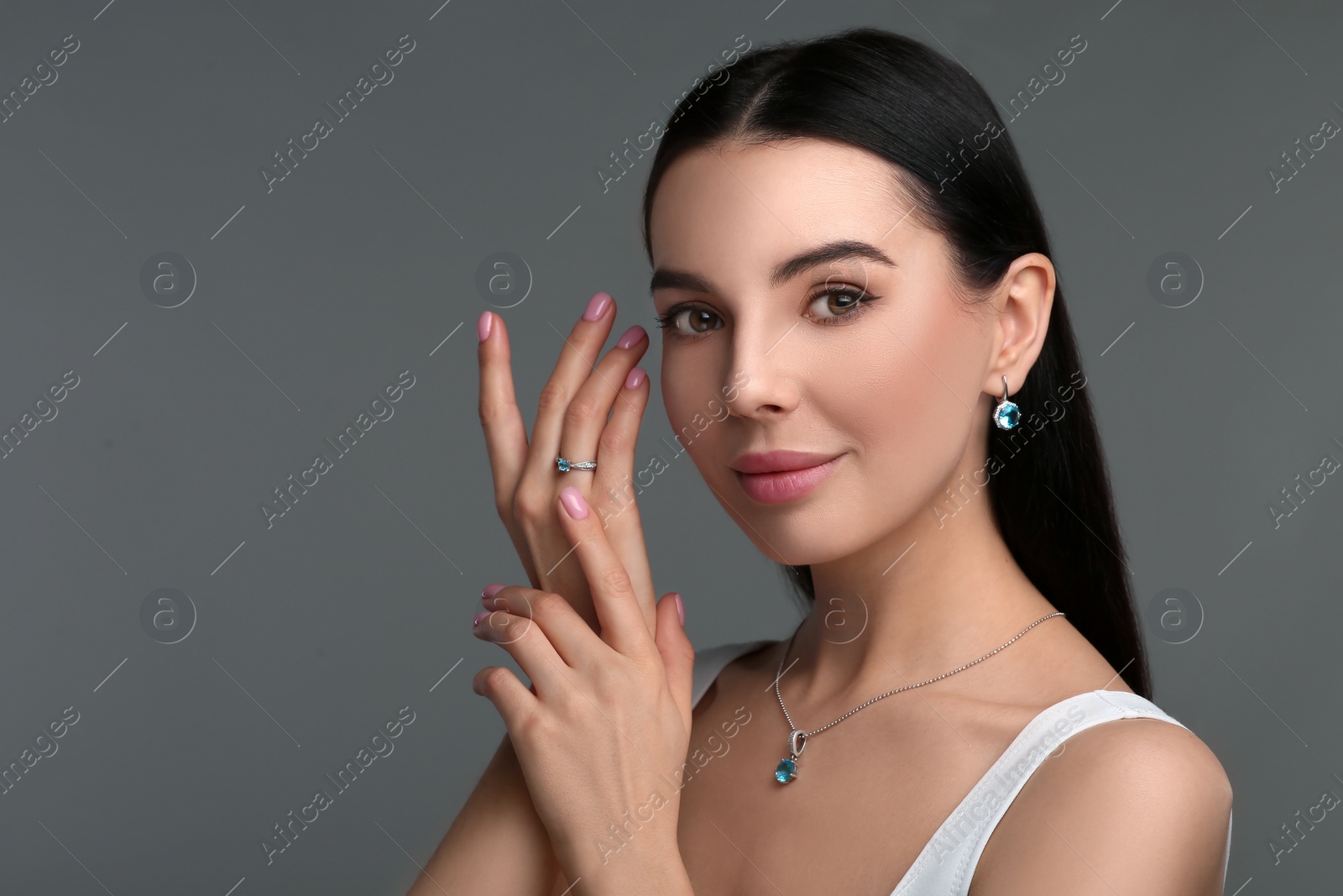 Photo of Beautiful young woman with elegant jewelry on dark grey background