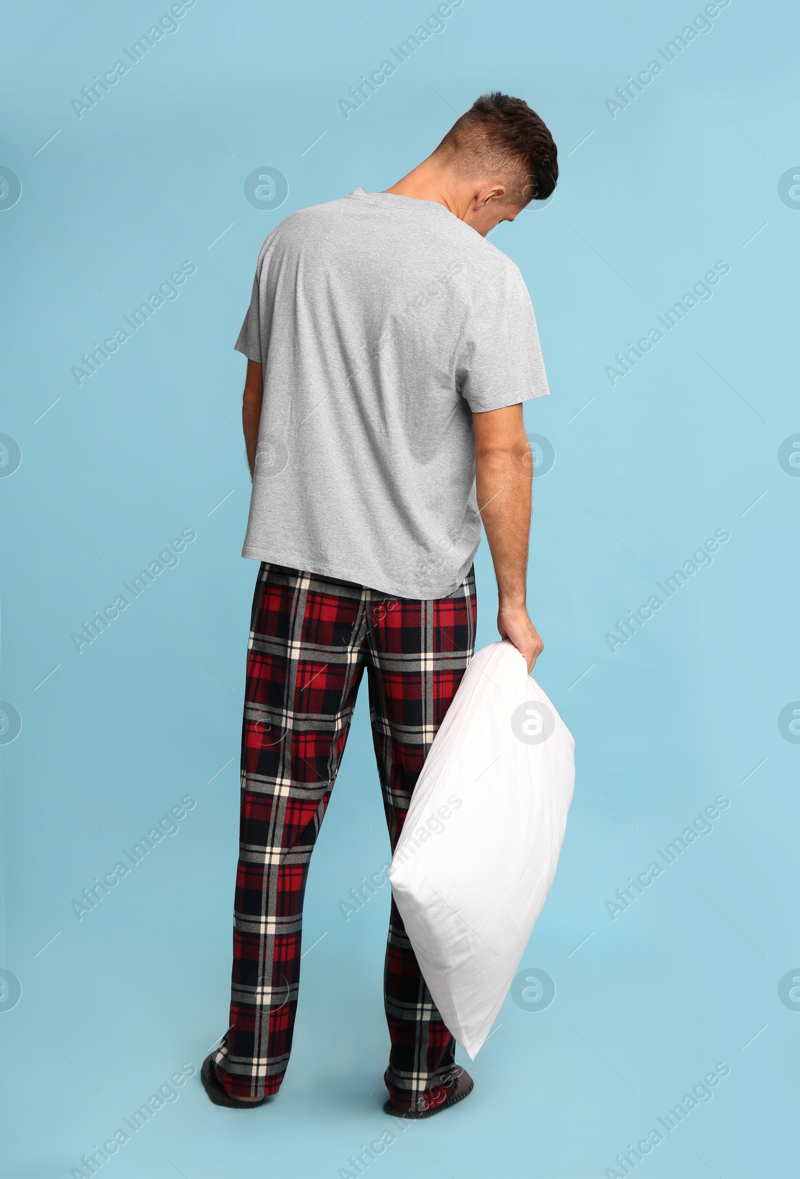 Photo of Somnambulist with soft pillow on light blue background. Sleepwalking