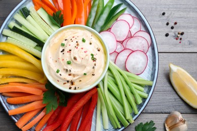 Photo of Fresh raw vegetable sticks and sauce on grey wooden table, flat lay